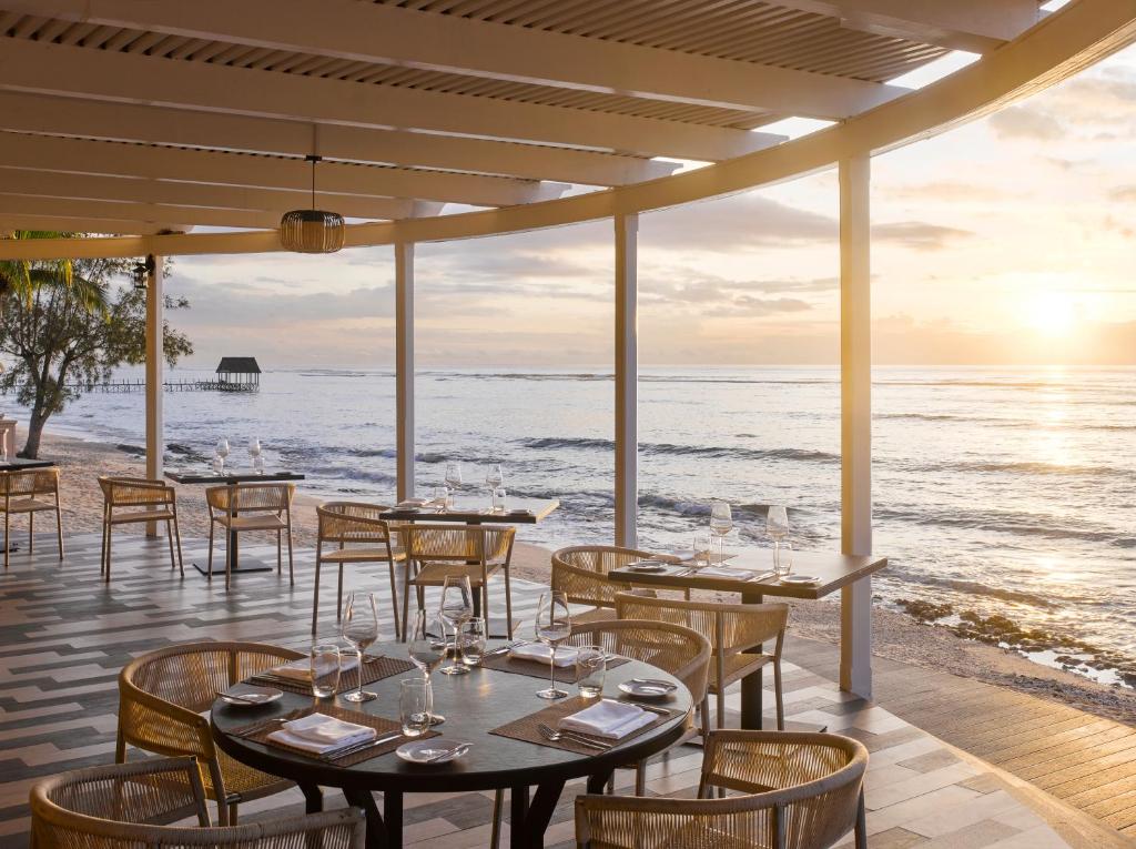 Open-air beachfront restaurant dining area overlooking the ocean at sunset Open-air beachfront restaurant dining area overlooking the ocean at sunset