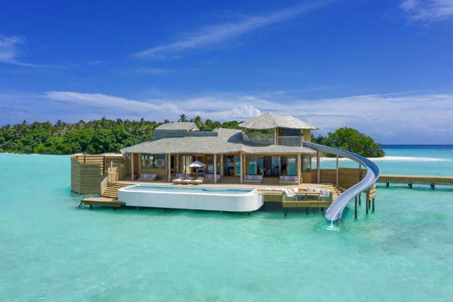 Luxury overwater villa with private pool and water slide into clear turquoise lagoon