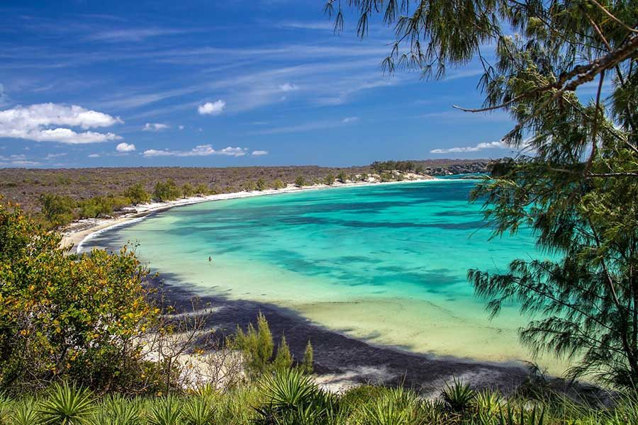 Turquoise lagoon bay with white sand beach, framed by coastal trees in Madagascar