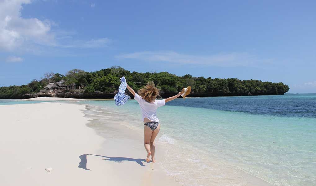 Woman enjoying a peaceful walk along a pristine Zanzibar beach. Woman enjoying a peaceful walk along a pristine Zanzibar beach.