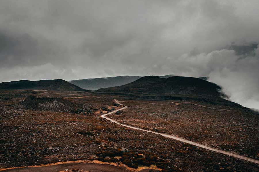 Winding dirt road through Réunion's volcanic highlands under low clouds Winding dirt road through Réunion's volcanic highlands under low clouds