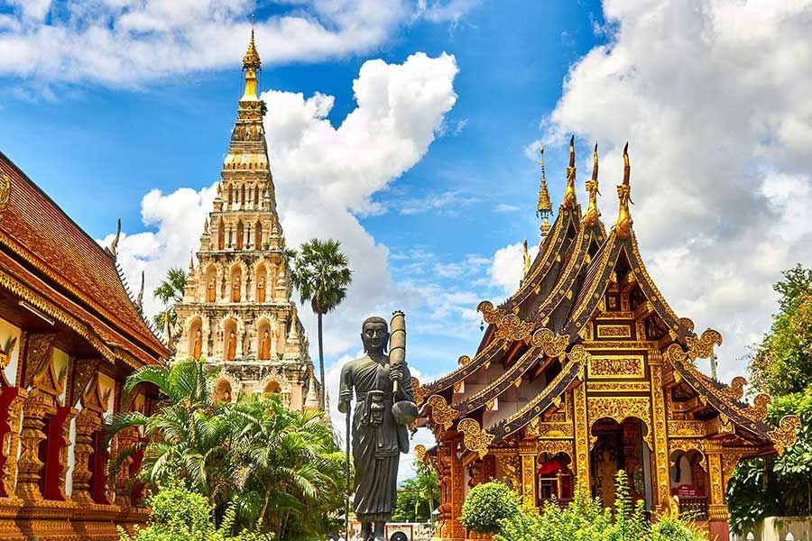 Golden Thai temple with an ornate spire and a standing Buddha statue Golden Thai temple with an ornate spire and a standing Buddha statue