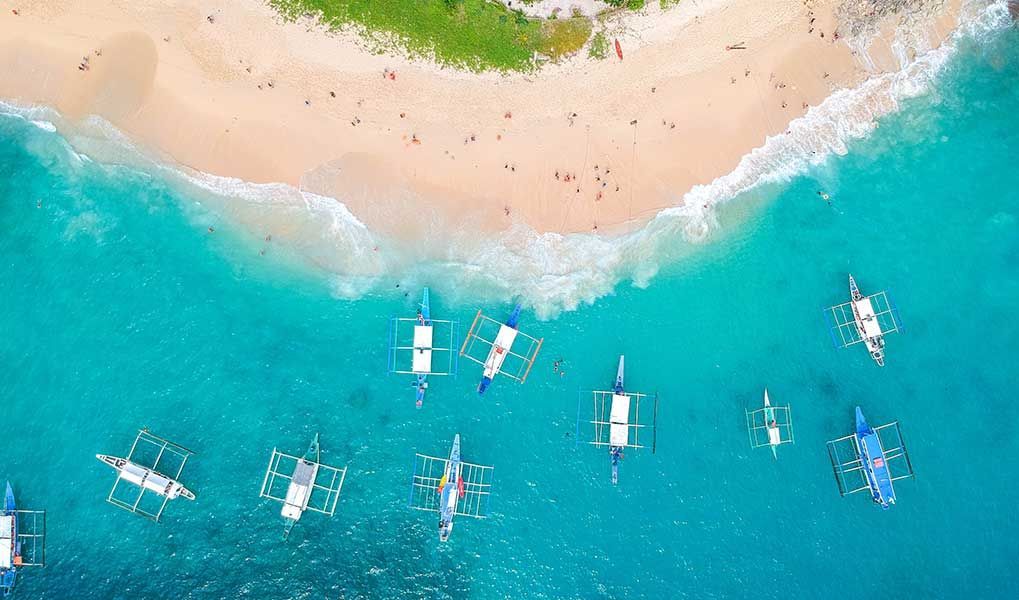 Aerial view of turquoise water and boats beside a tropical beach. Aerial view of turquoise water and boats beside a tropical beach.
