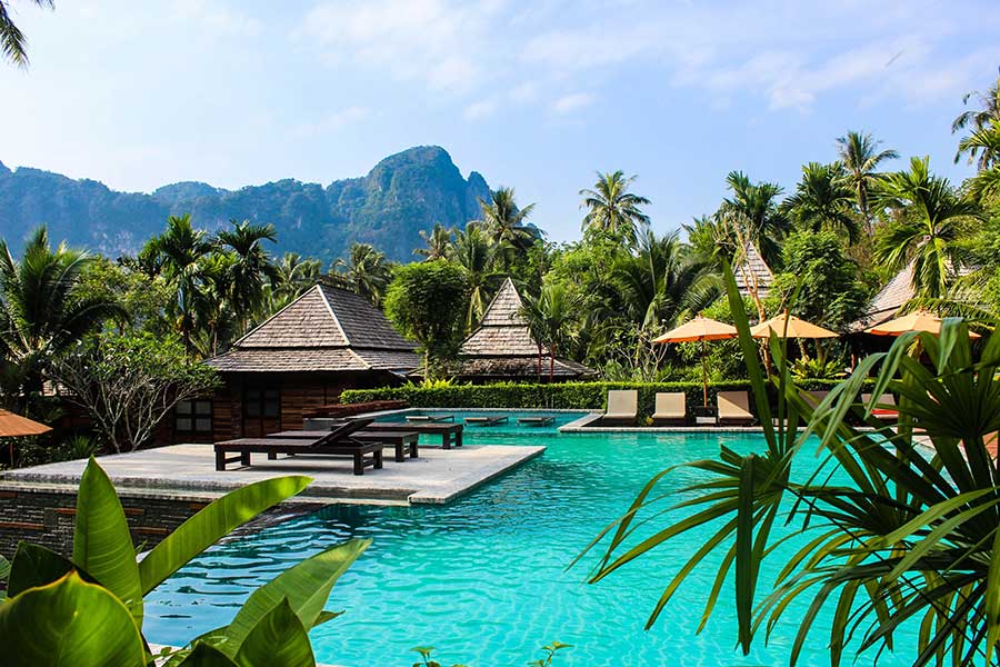 Tropical resort pool with sun loungers, palm trees, and mountain views Tropical resort pool with sun loungers, palm trees, and mountain views