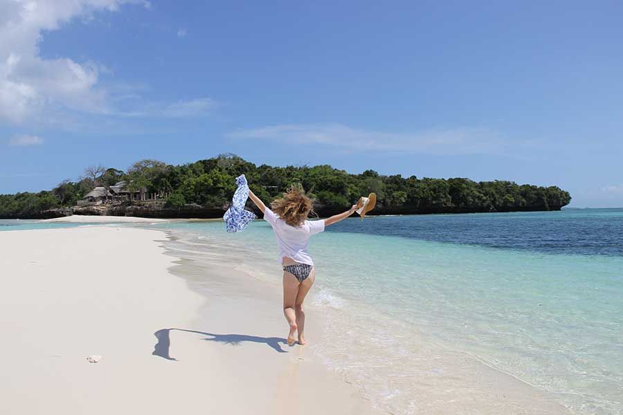 Woman enjoying a quiet walk along a pristine Zanzibar beach. Woman enjoying a quiet walk along a pristine Zanzibar beach.
