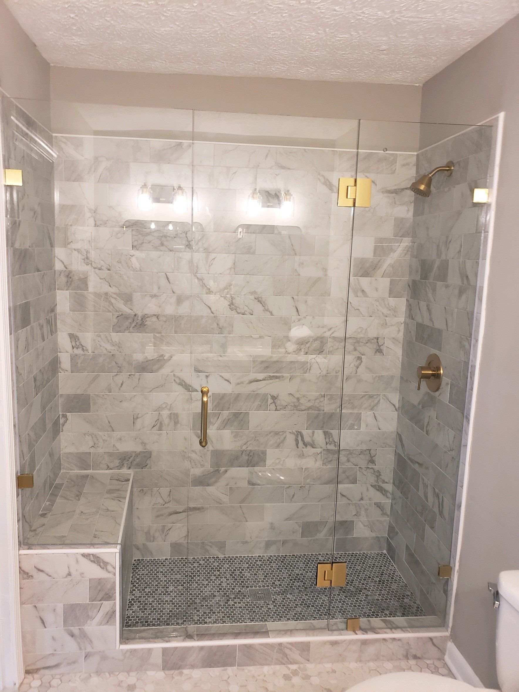 marble subway tile with gold hardware glass enclosure