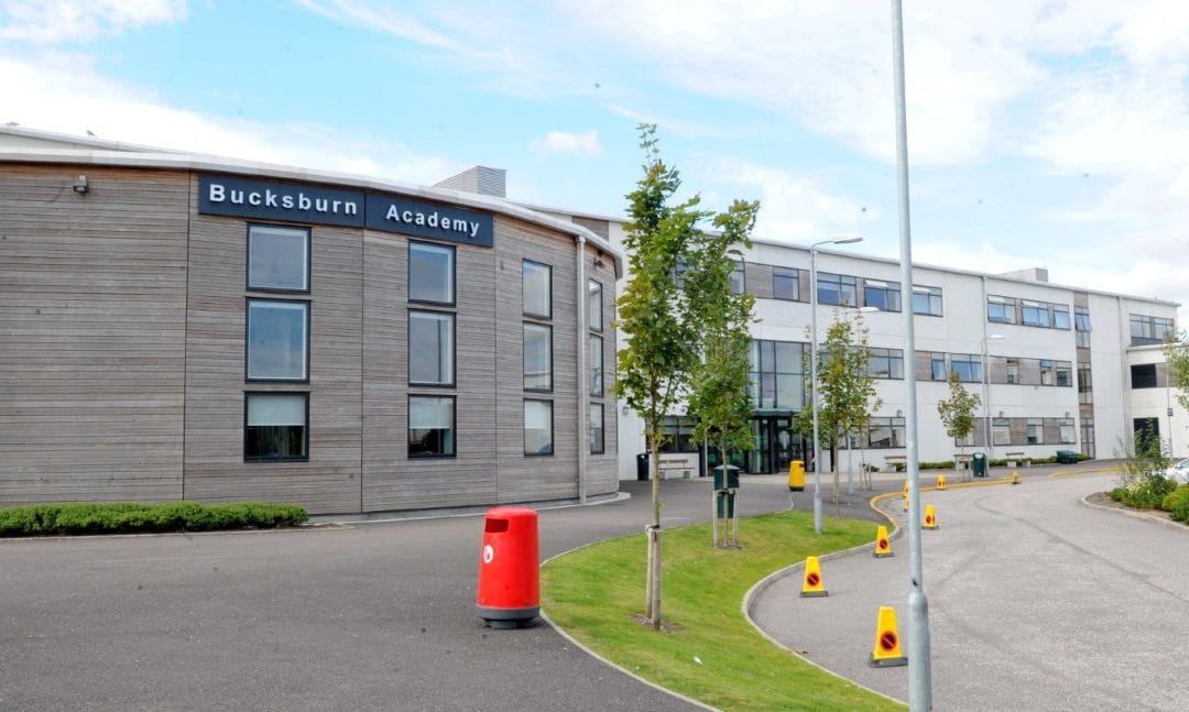 A picture of a school containing text, sky, road and traffic cones