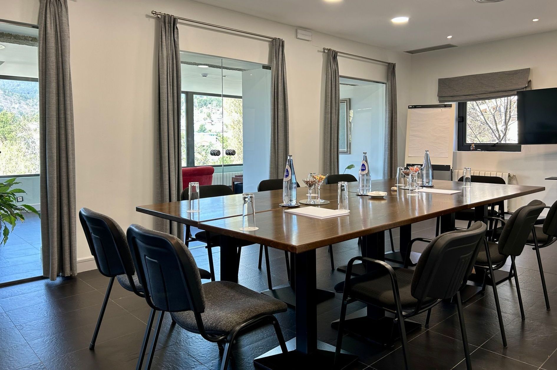 Mesa de juntas con proyector, blocs, bolígrafos y agua en la sala de reuniones de Luces del Poniente, ideal para sesiones corporativas profesionales