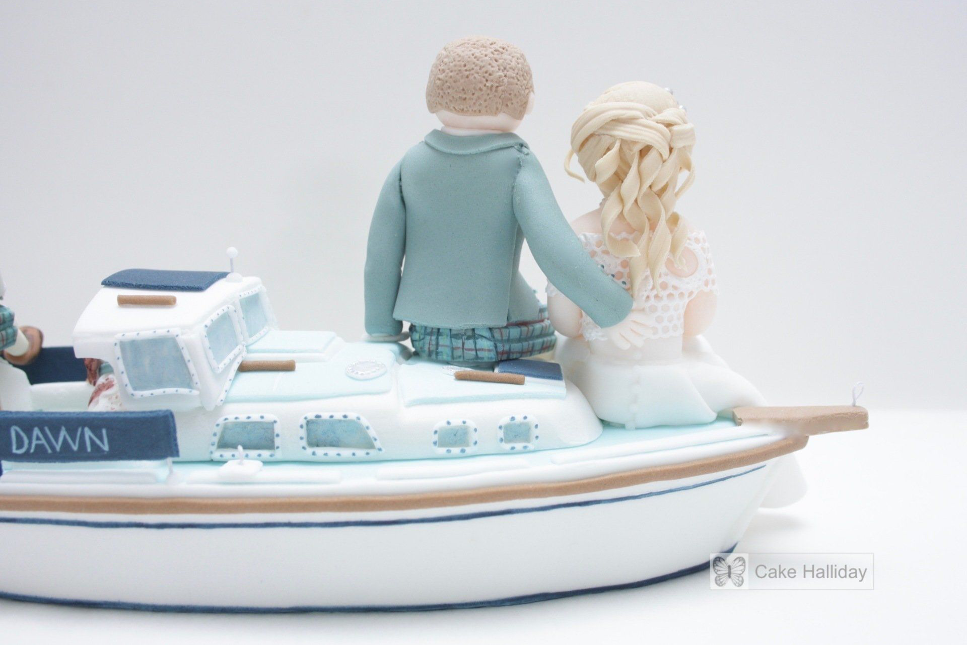 Bride & groom wedding cake topper, sitting on top of their sugar yacht
