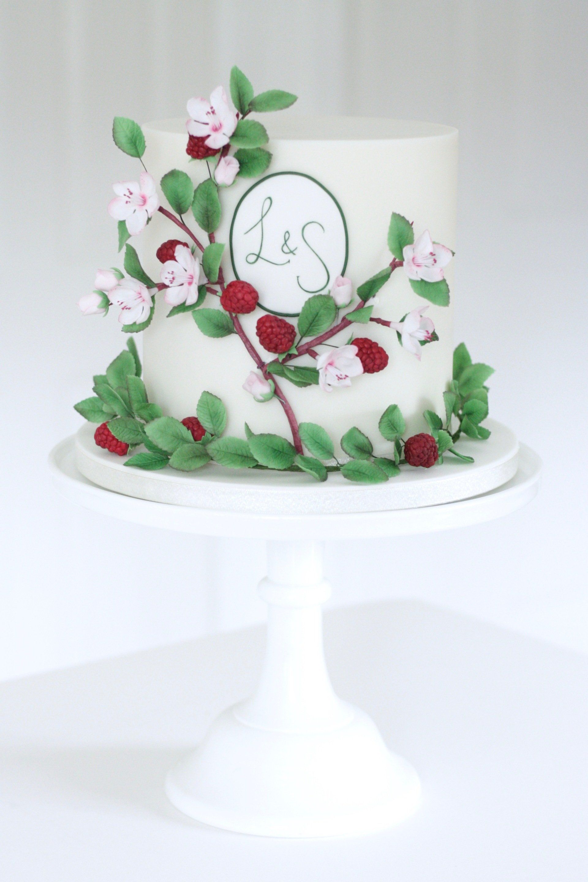 Single tier wedding cake with cherry blossoms and raspberries