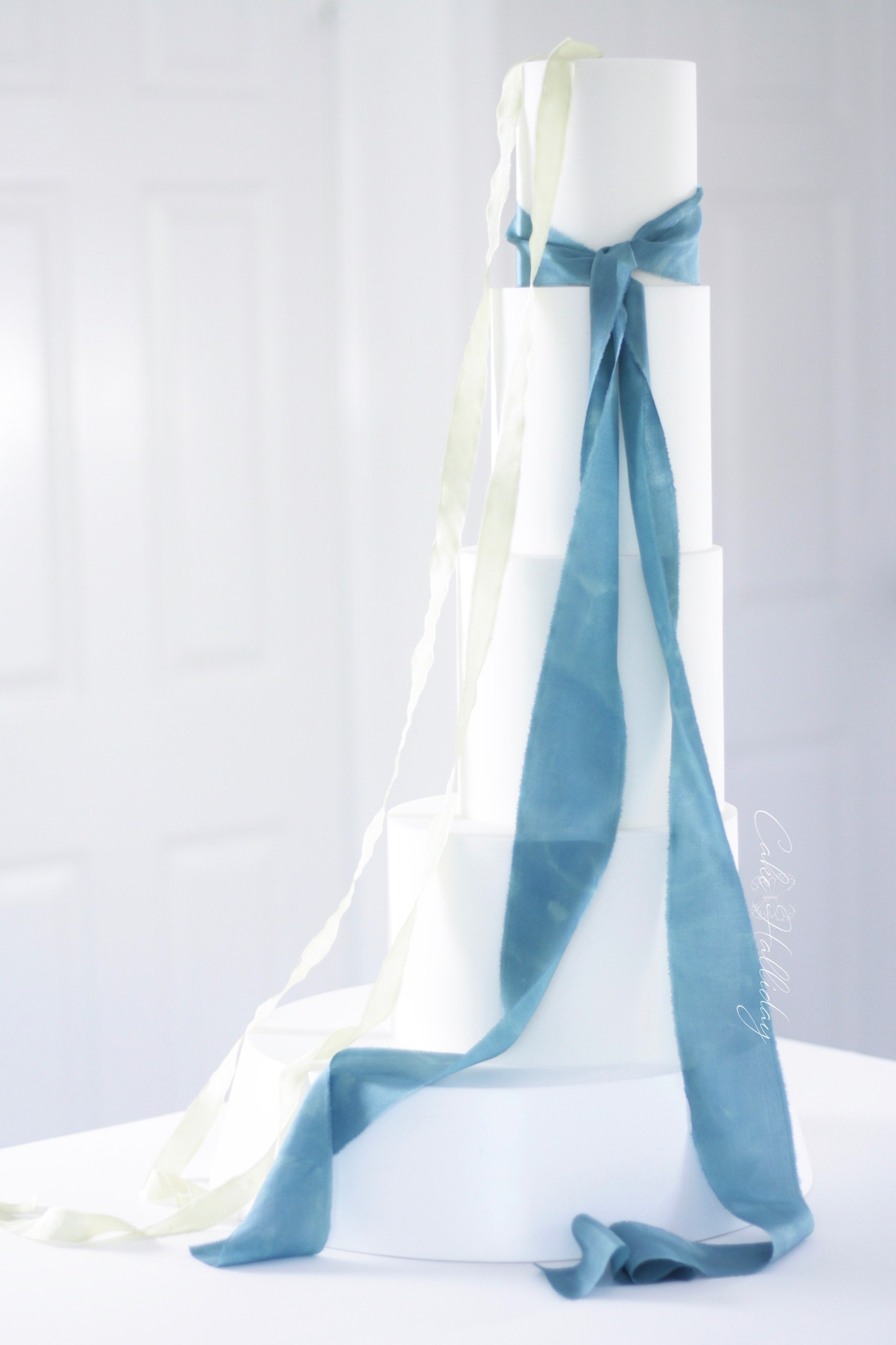 Four tier minimalist wedding cake with teal and lime silk ribbons