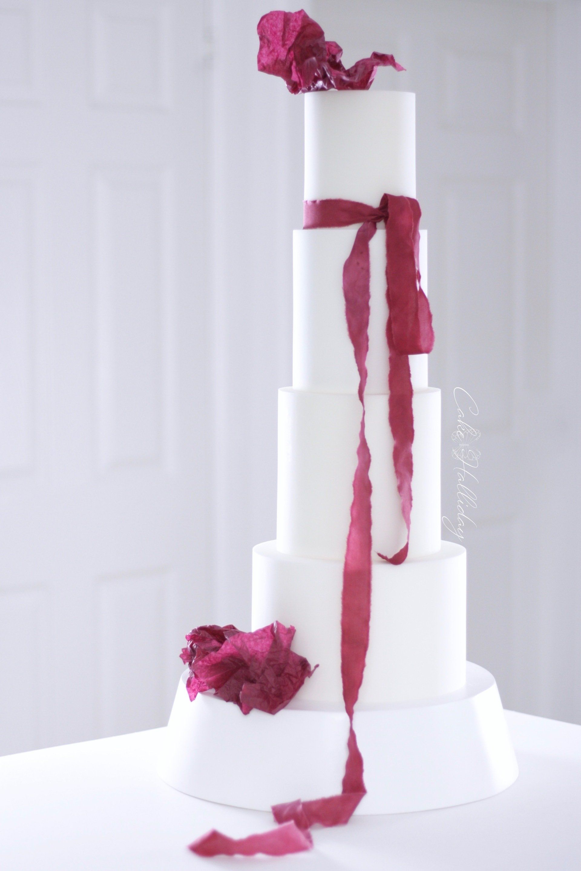 Four tier wedding cake with burgundy silk ribbon