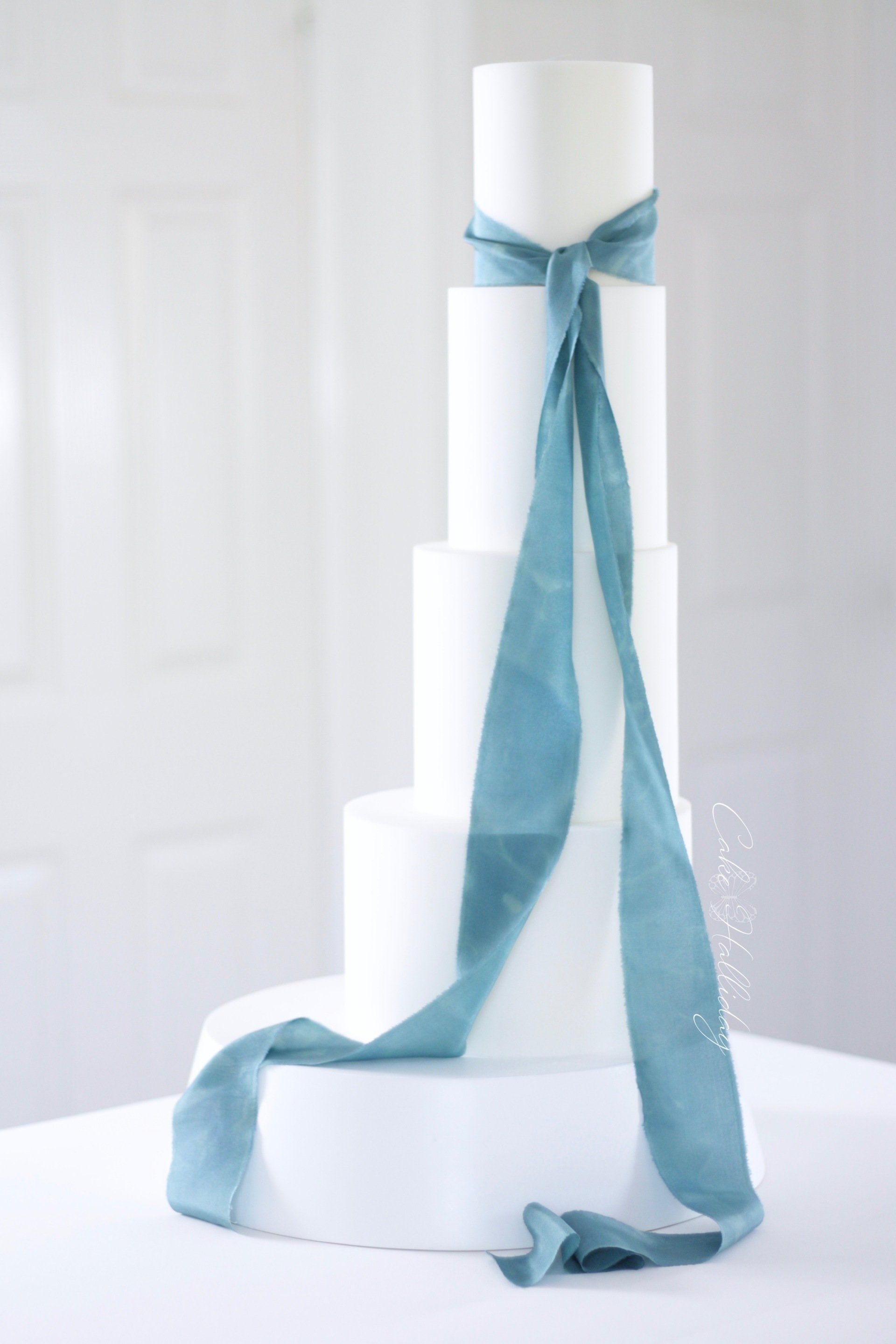 Four tier minimalist wedding cake with teal silk ribbon