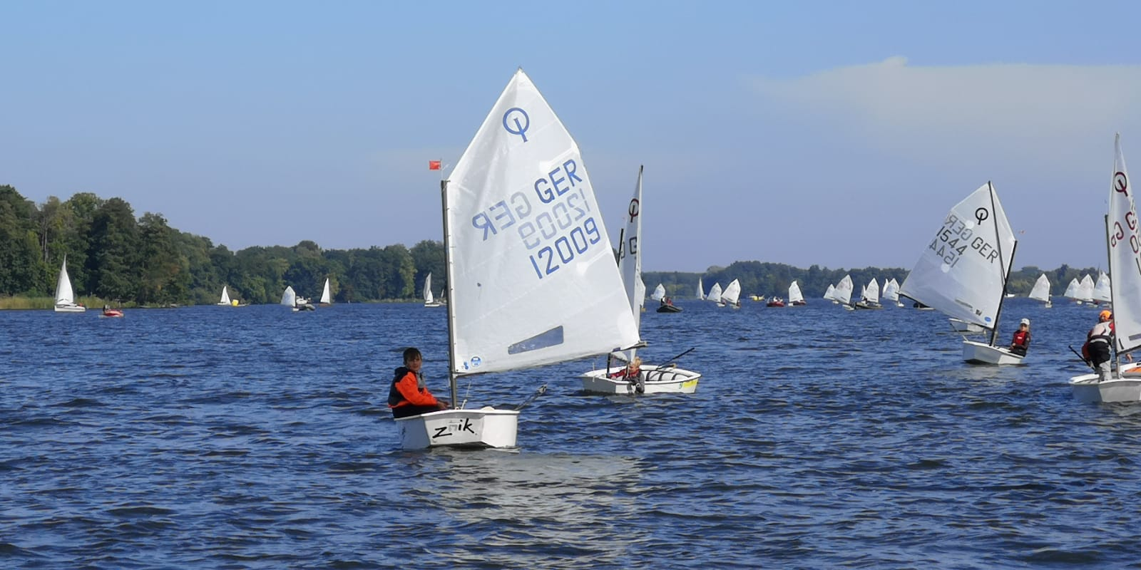 Zeigt kleine Segelboote mit Kindern sog. Optimisten