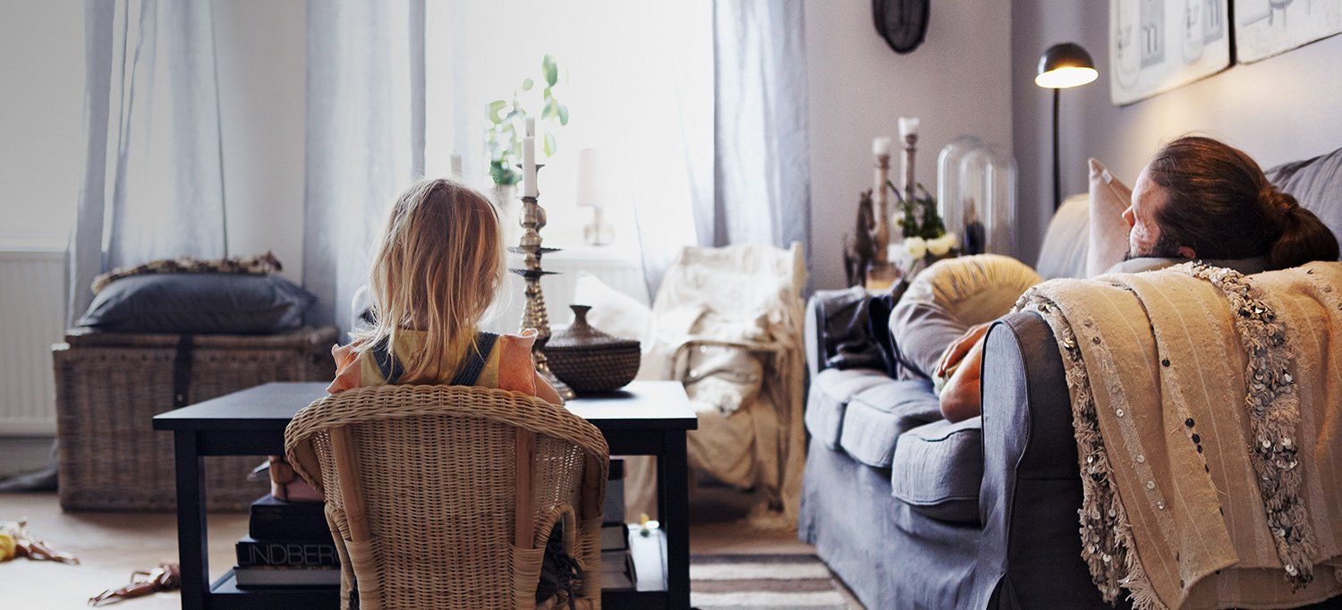 padre e hijo de espaldas sentados en el salón de su casa