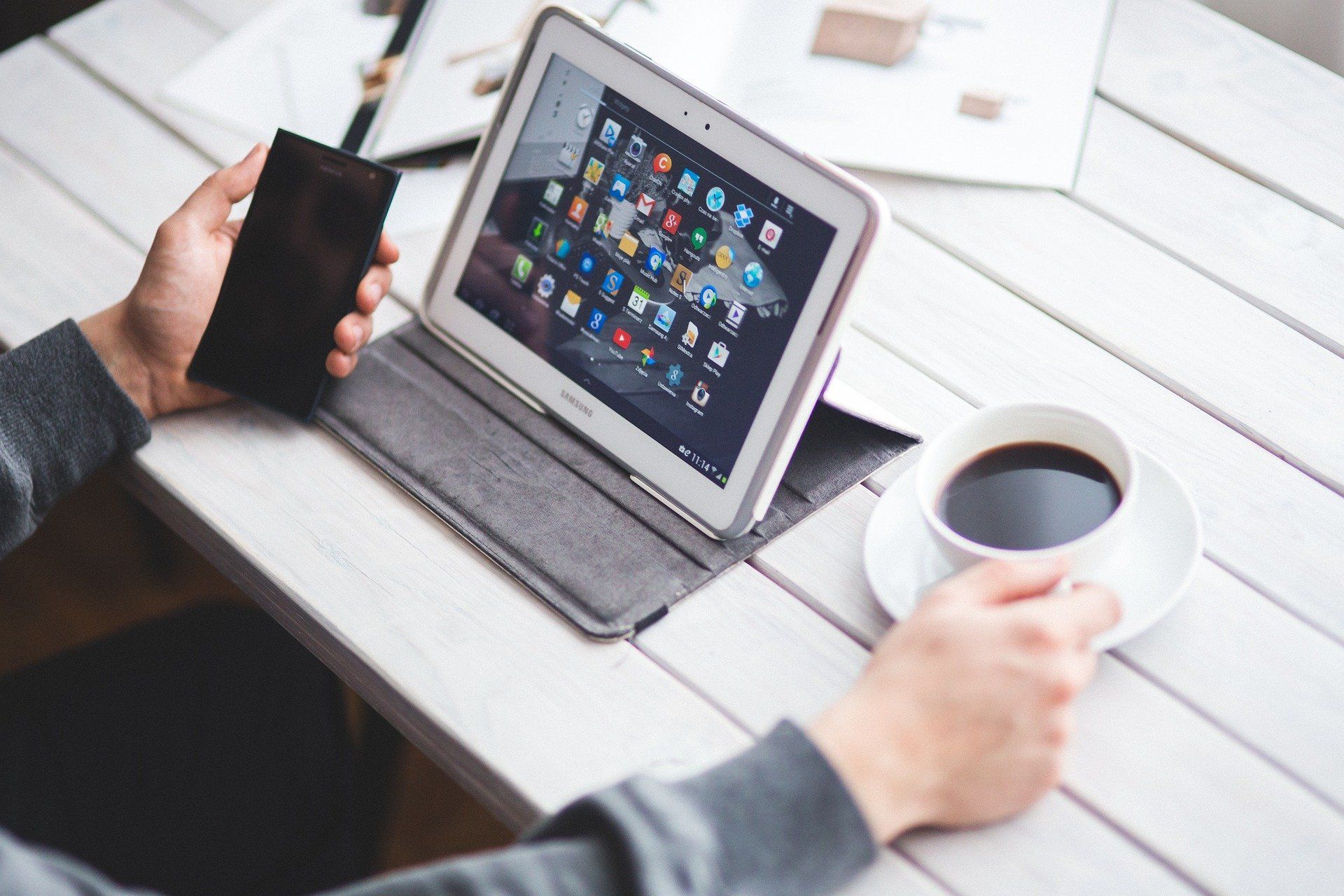 Mitarbeiter mit Tablet, Smartphone und Kaffeetasse
