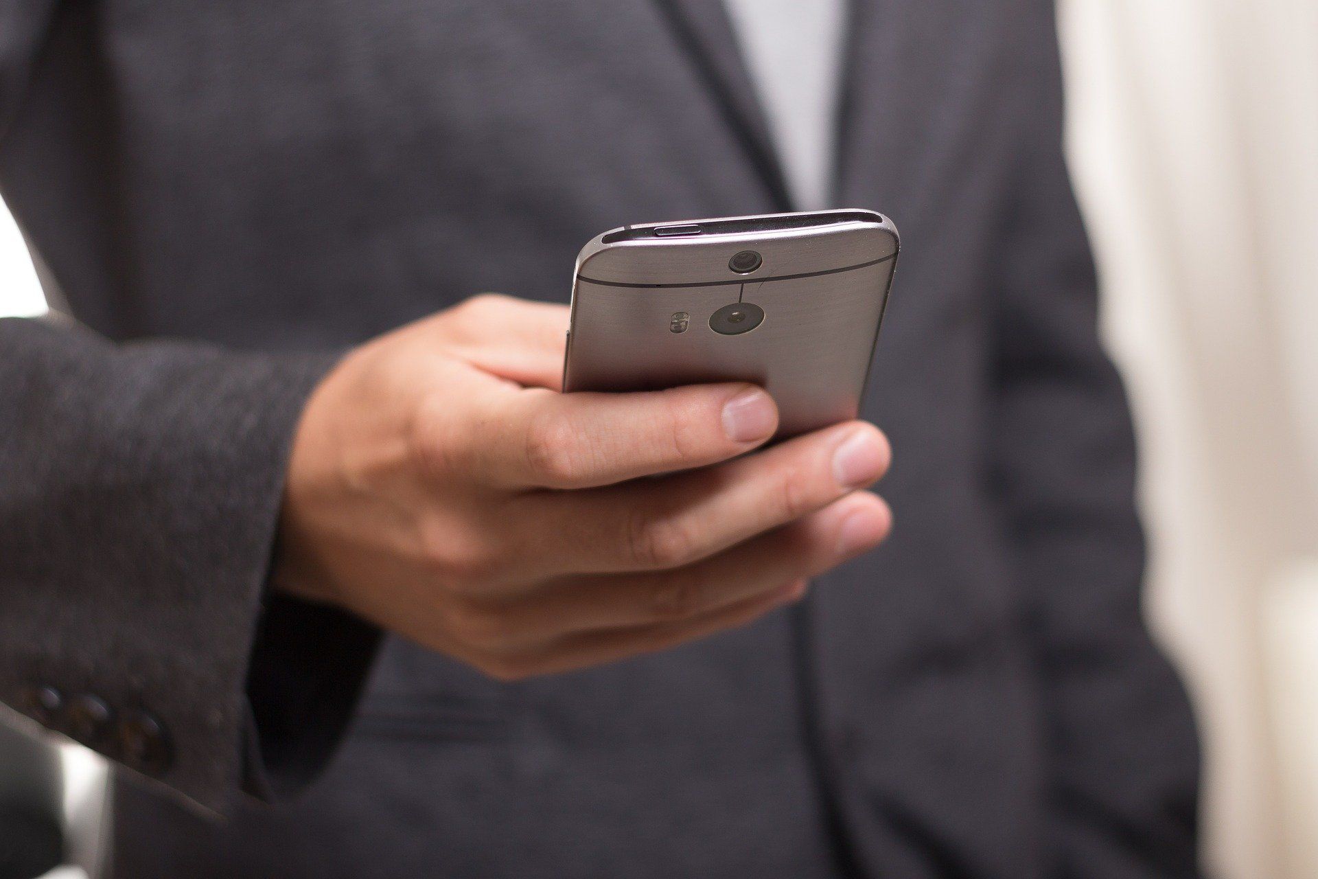 Person in Businesskleidung mit Smartphone in der Hand