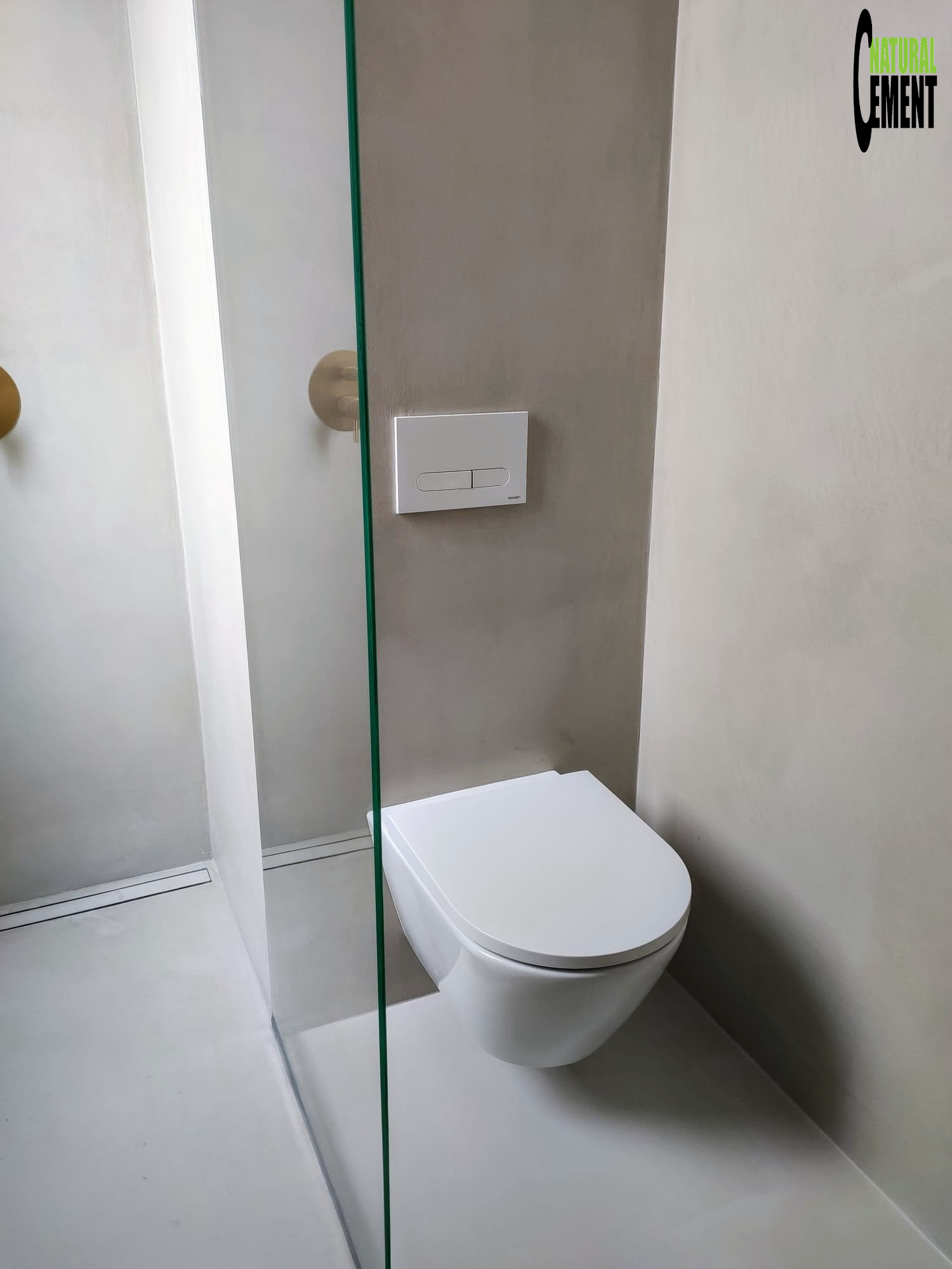 Diseño de baño con microcemento en tonos tierra y hornacina iluminada en la ducha.