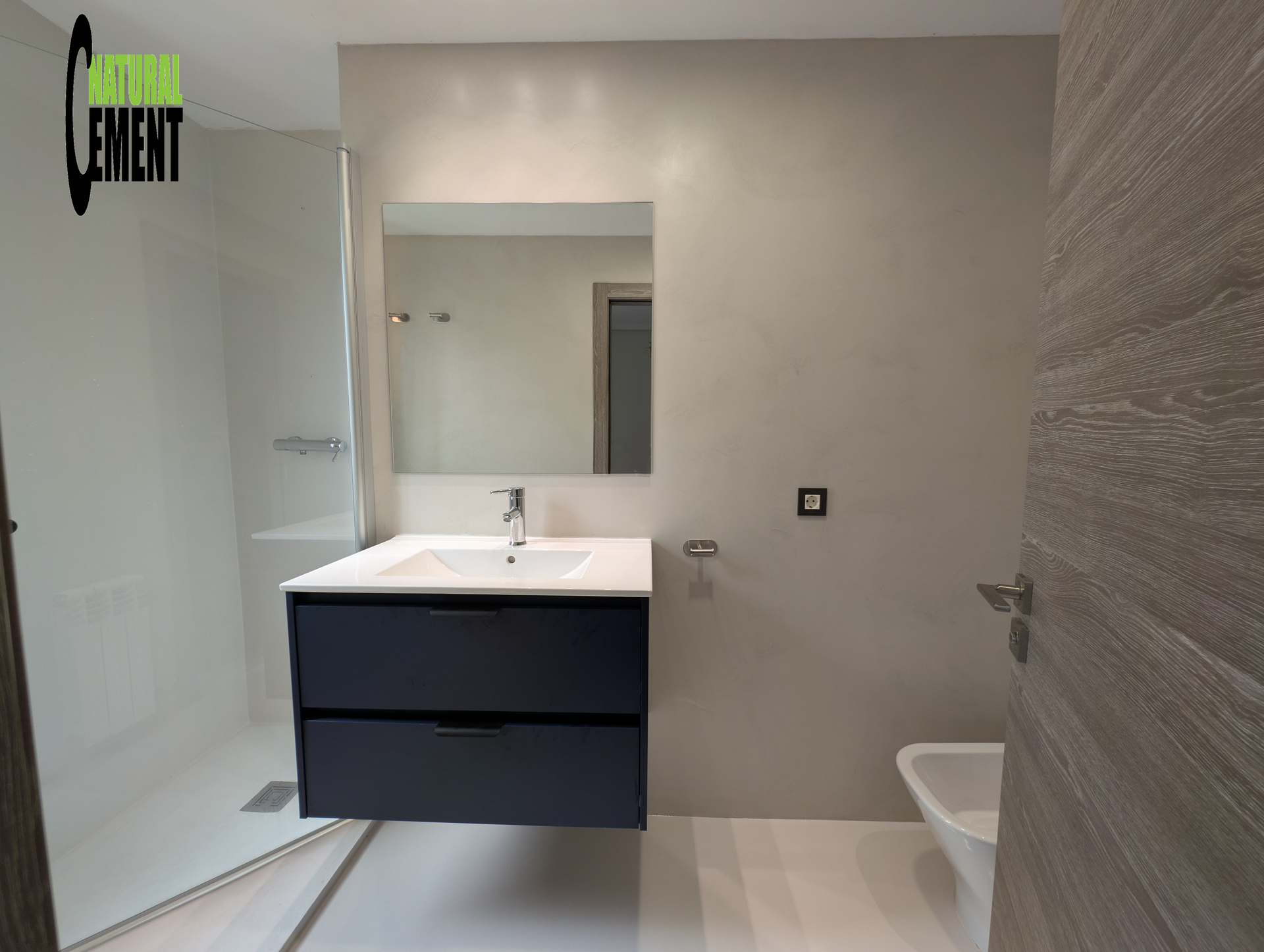 Baño minimalista con microcemento claro en paredes y suelo, creando un espacio sereno.