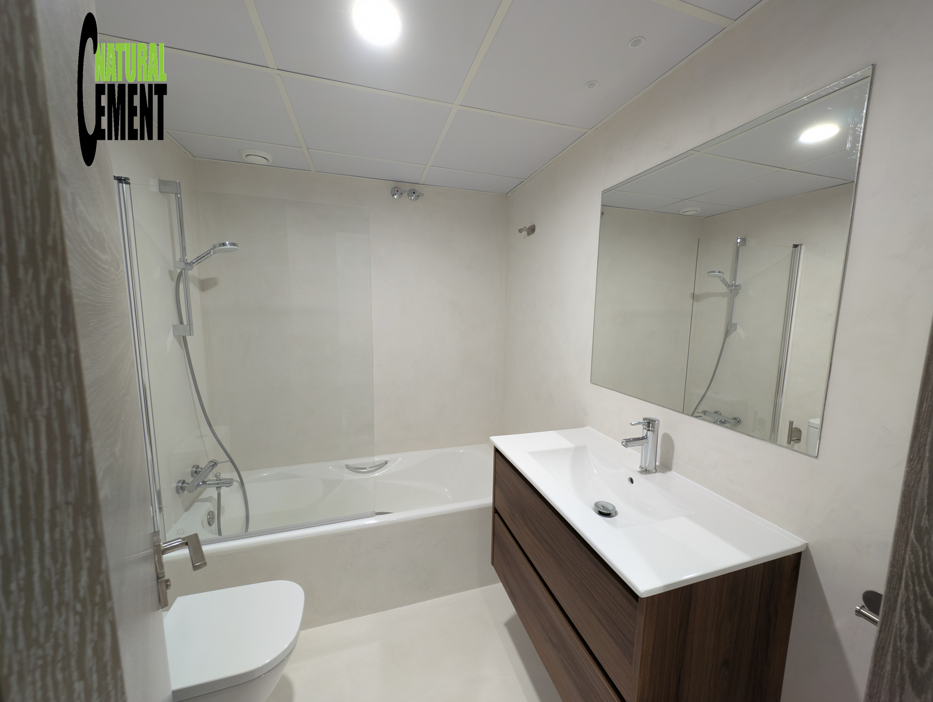 Baño con bañera exenta y paredes revestidas de microcemento efecto piedra natural.