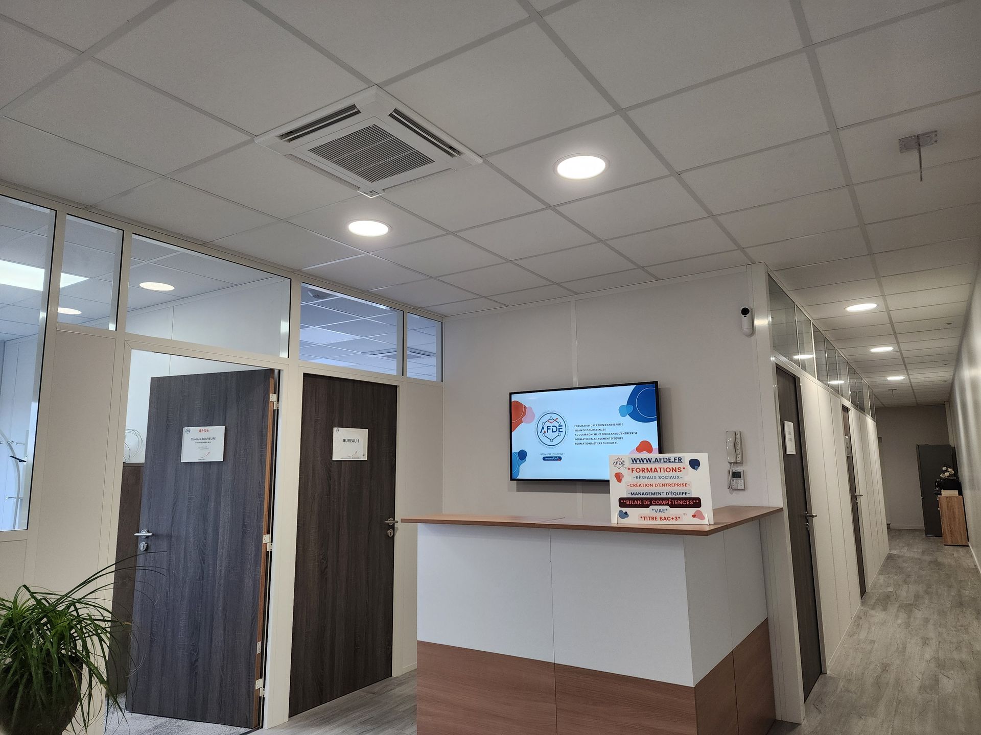 Organisme de formation Bourg-de-Péage Réunion avec des employés d'AFDE assis autour d'une table, mains levées.