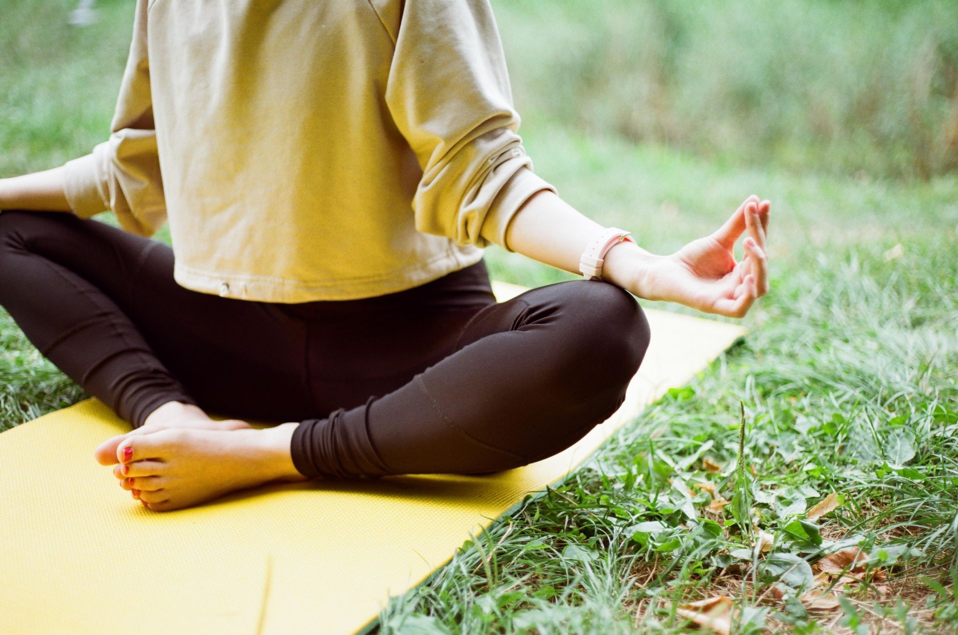 Photo d'une personne faisant de la méditation en extérieur sur un tapis pour gérer son stress.