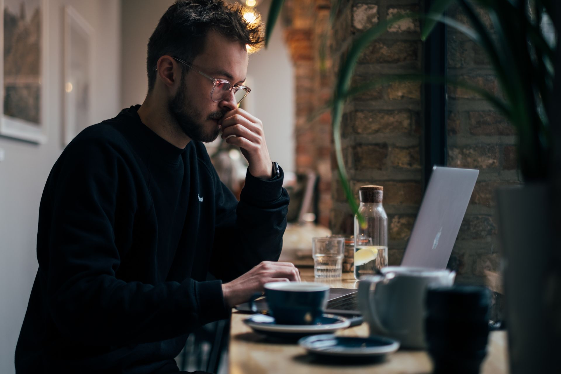 homme travaillant sur son ordinateur à un café, réfléchissant à sa carrière.