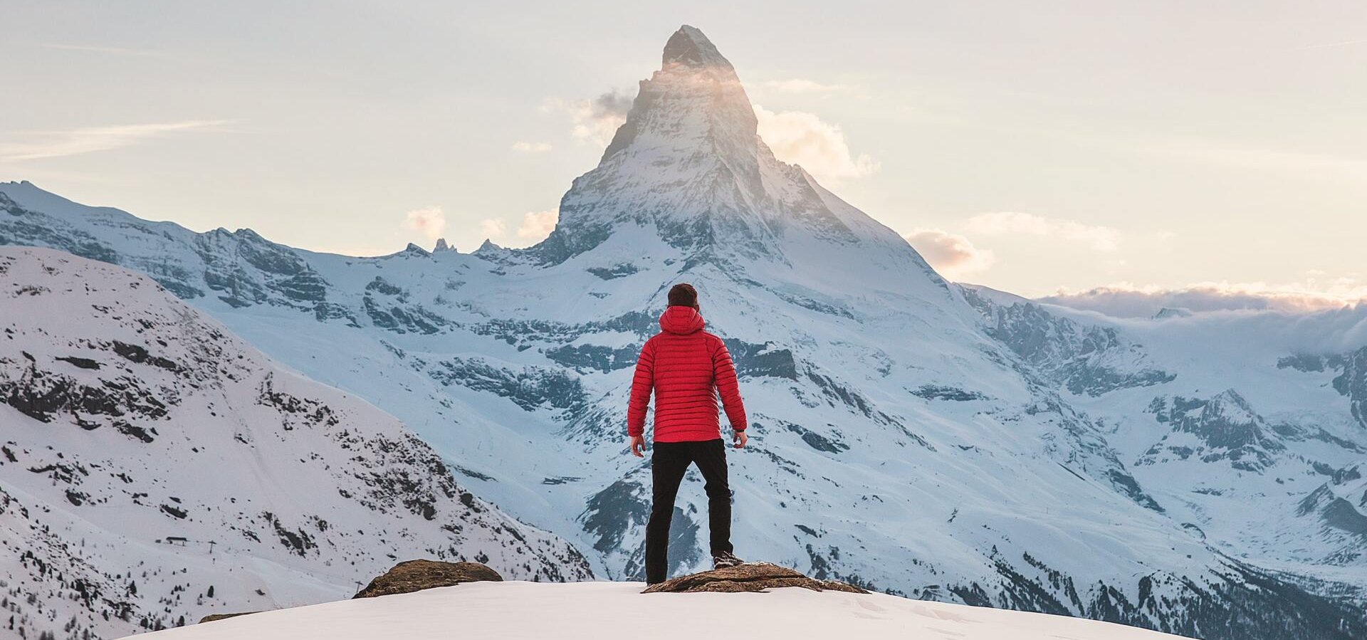 Un homme debout devant une montagne, qu'il doit gravir symbolisant la zone de confort.