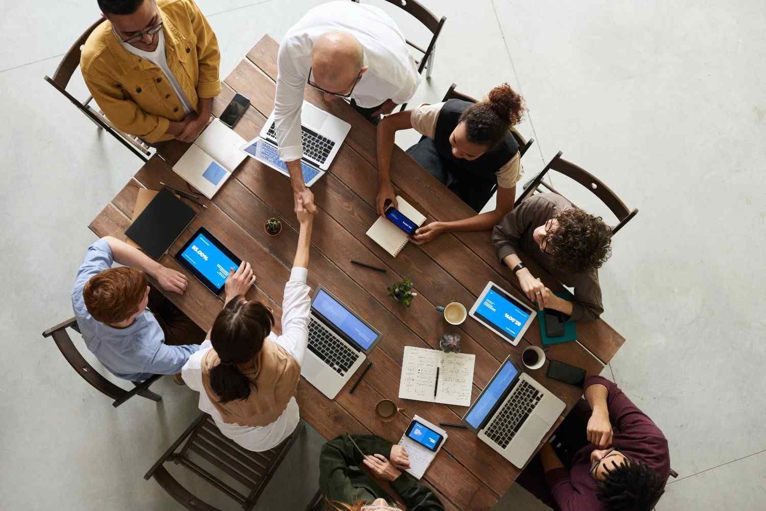 Un groupe d'experts en gestion de TPE assis autour d'une table avec des ordinateurs portables.