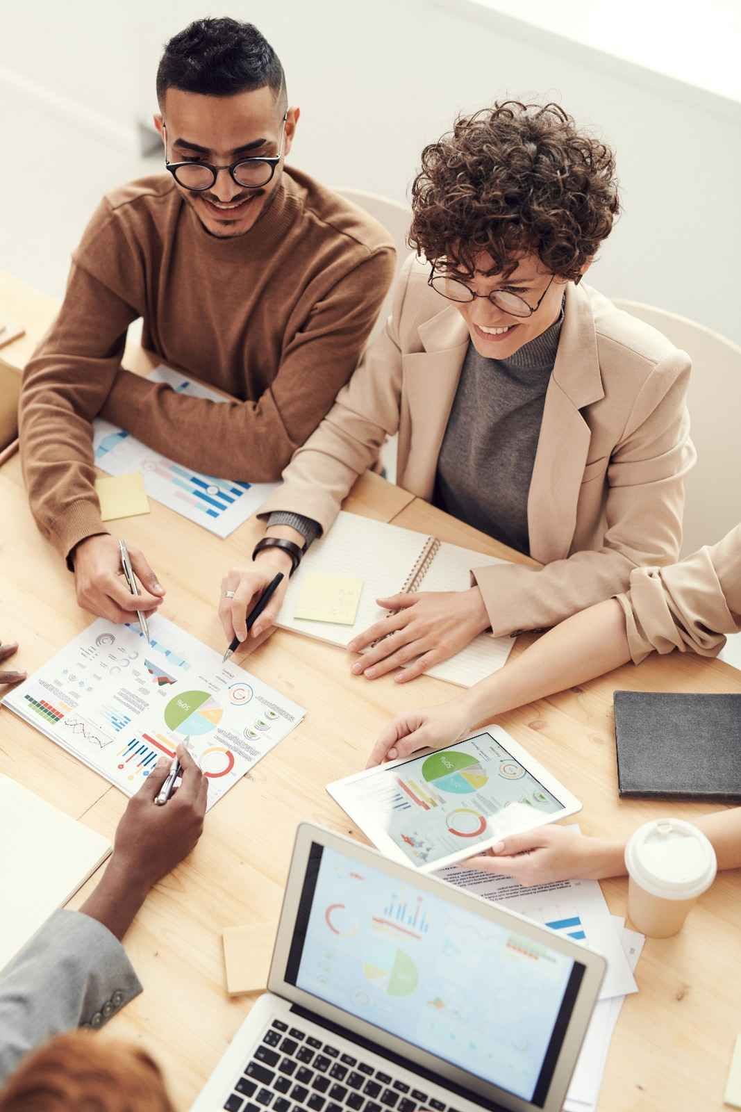 Groupe de personnes autour d'une table pointant vers des graphiques imprimés sur des feuilles.