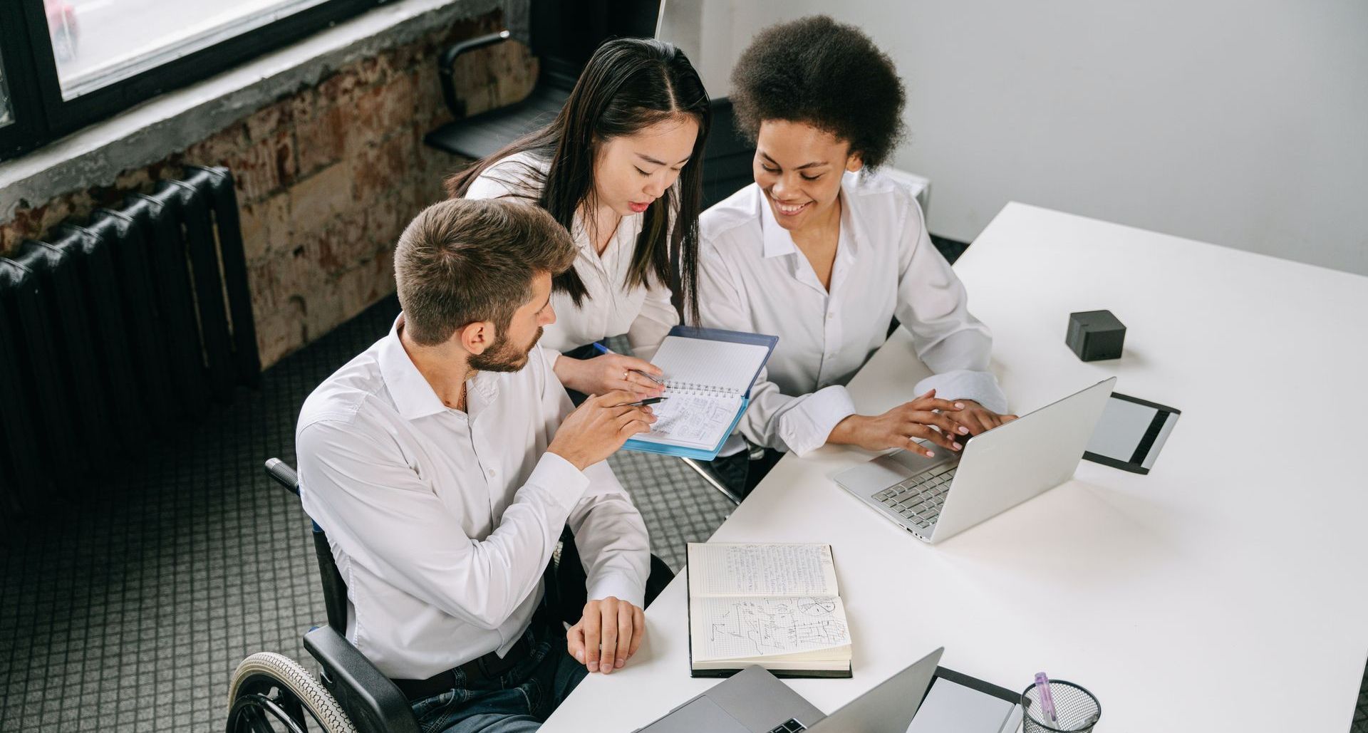 Trois personnes dans une salle de réunion avec des ordinateurs portables et des papiers.
