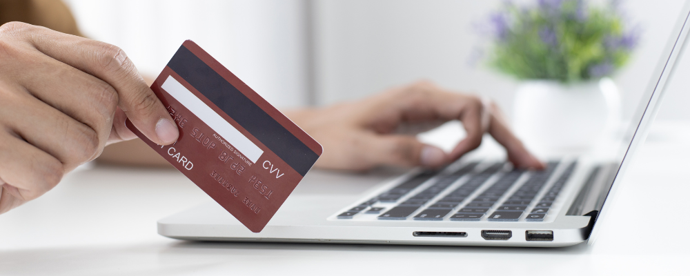 Personne tenant une carte de crédit et tapant sur un ordinateur portable pour un paiement en ligne