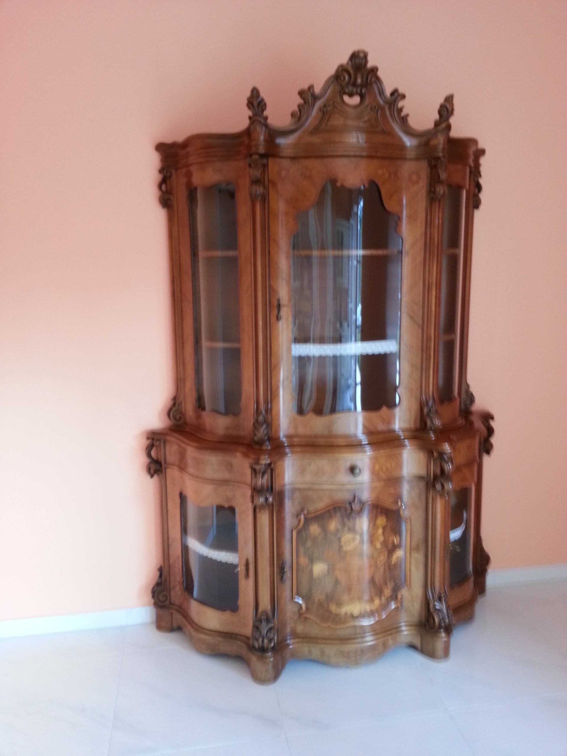 Antiker Schrank mit Glasfront und feinen Holzschnitzereien.