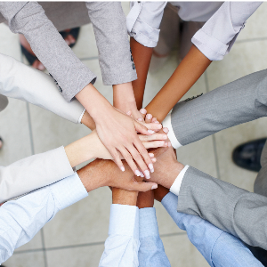 Viele Hände verschiedener Nationalitäten greifen übereinander in einem Team-Setting.
