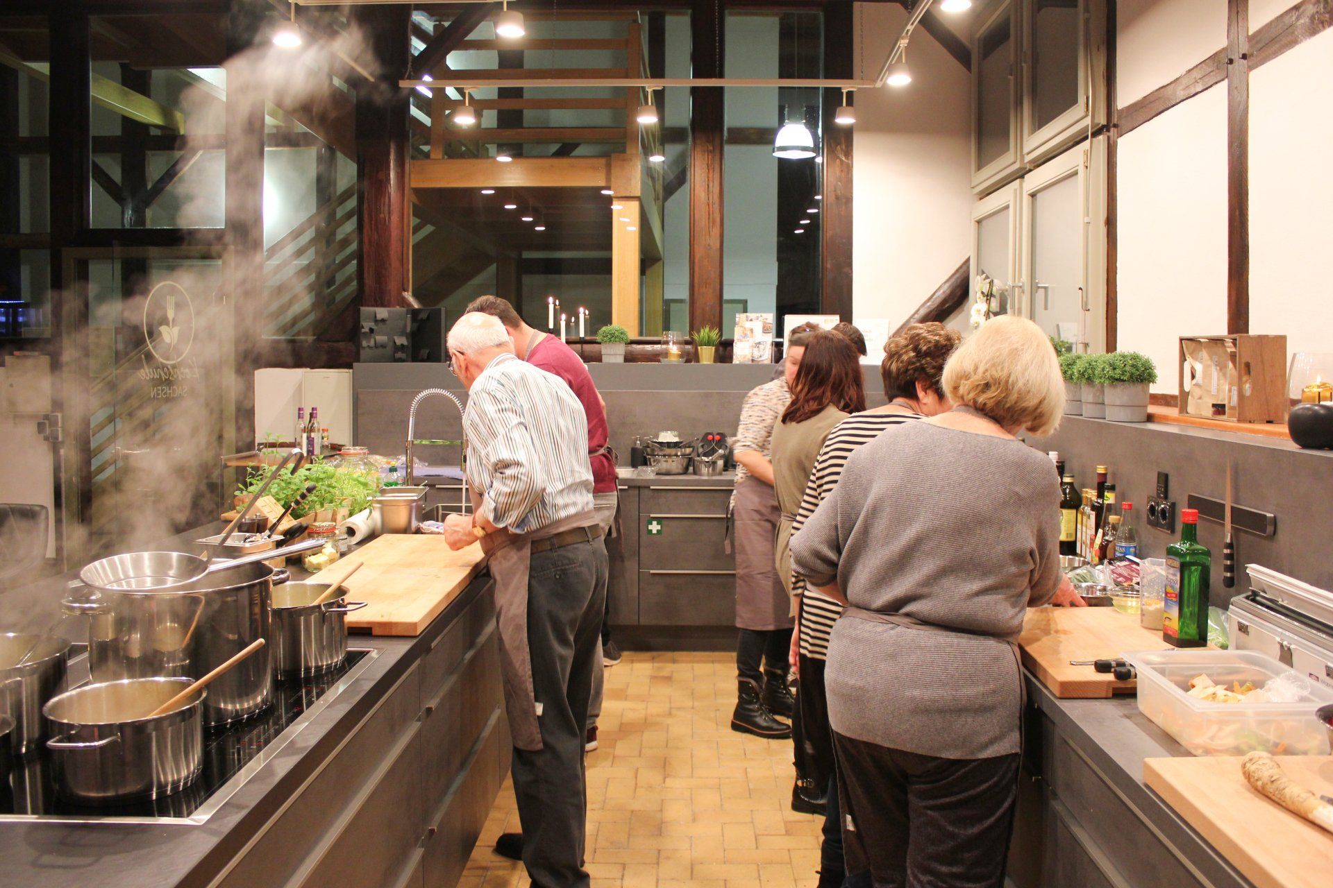 Foto von der Küche der Kochschule mit Teilnehmern, die darin kochen