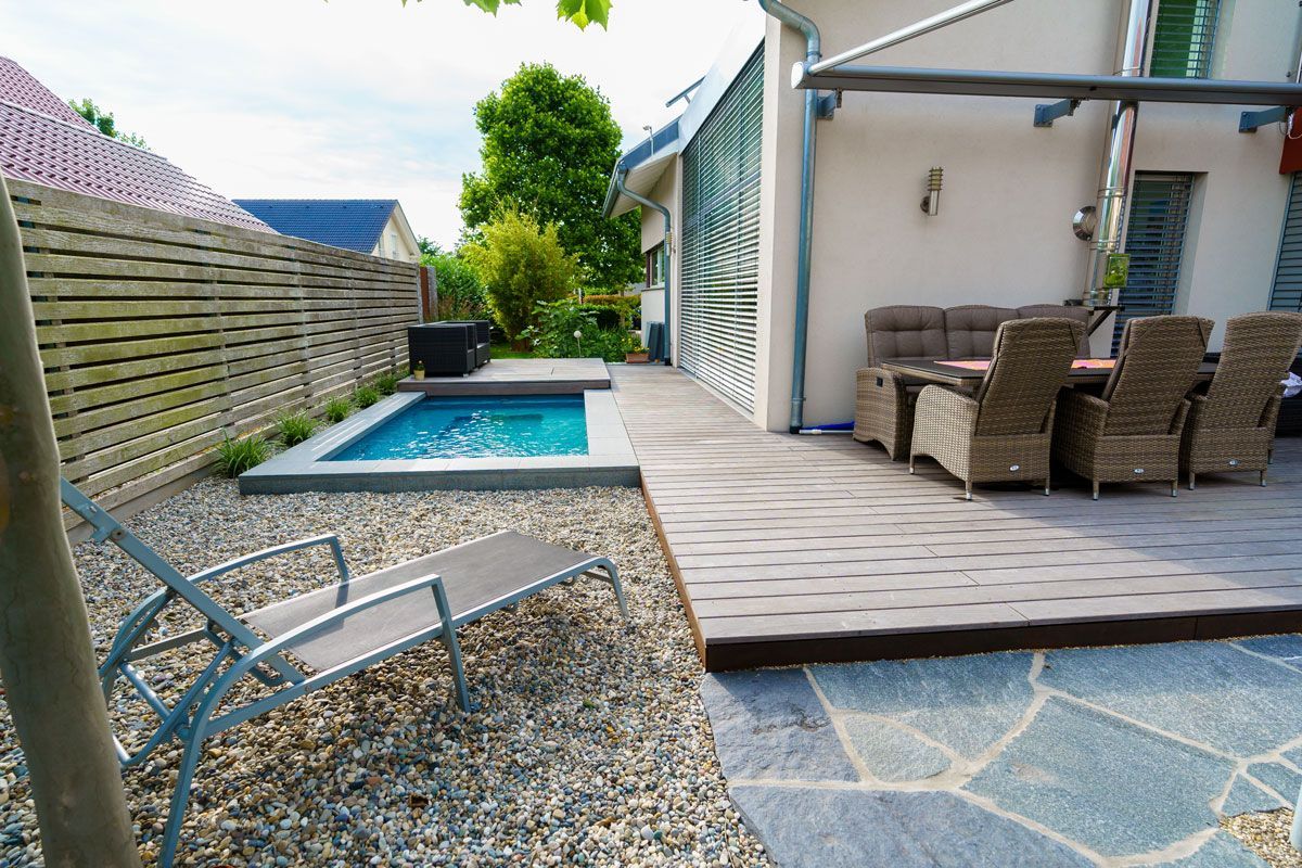 Pool bei Privathaus und Sitzplatz aus Holzdielen sowie Natursteinfläche