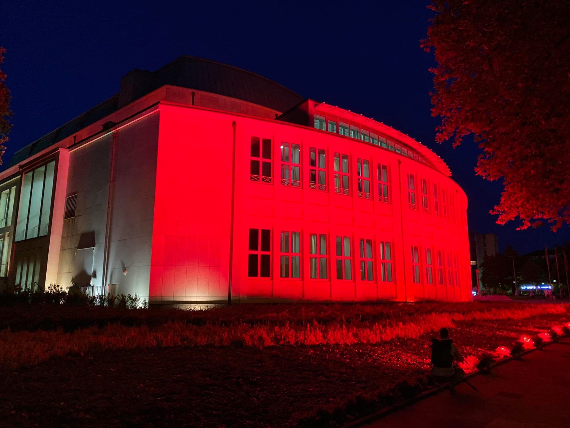 Philharmonie Essen, nachts, angestrahlt von roten Scheinwerfern