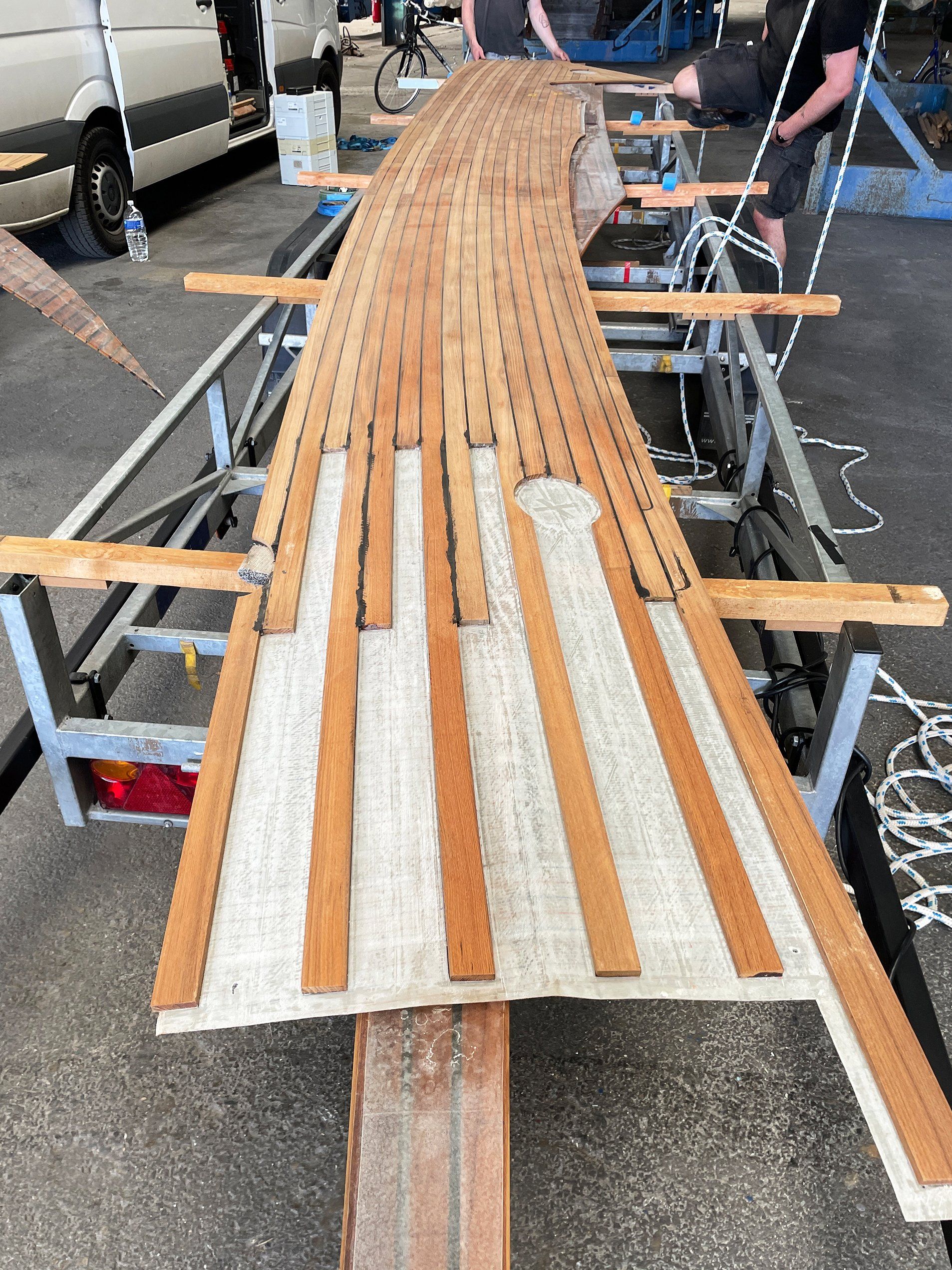 Transport of a teak deck deck panel, the layer of epoxy resin is visible as preparation for teak deck installation on a Futuna 57 sailing yacht by Mobilerbootsbau boat builder company