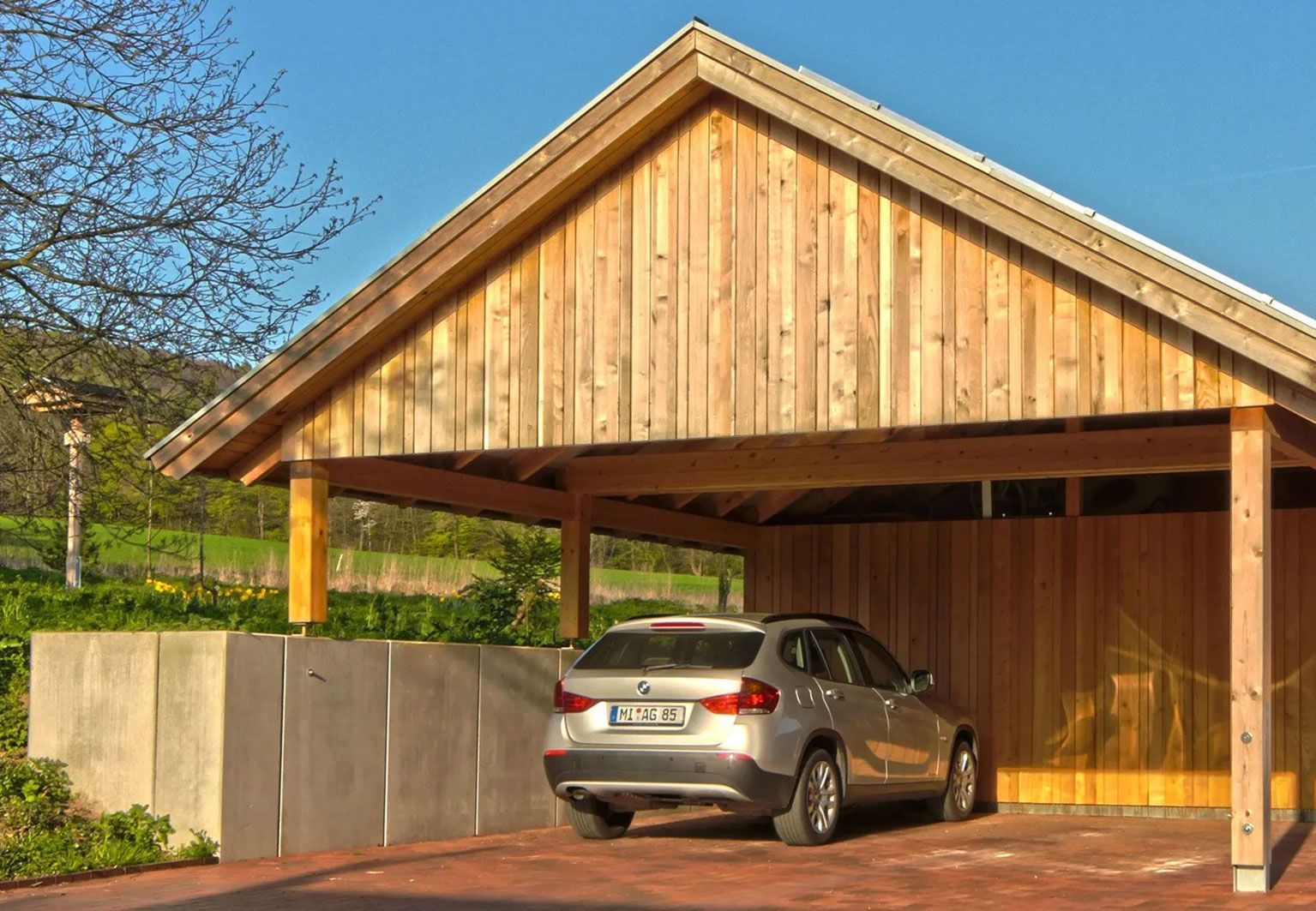 Ein Holz-Carport mit einem untergestellten silbernen Auto