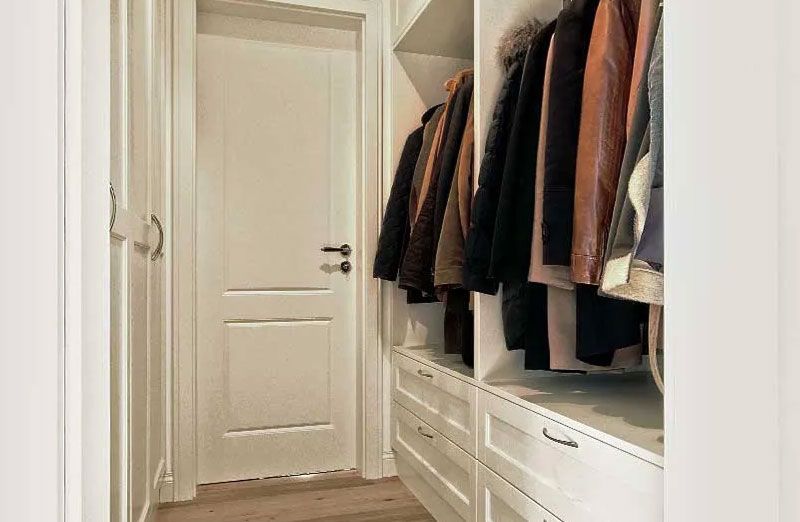 Ein weißer Einbauschrank mit eingehängter Kleidung