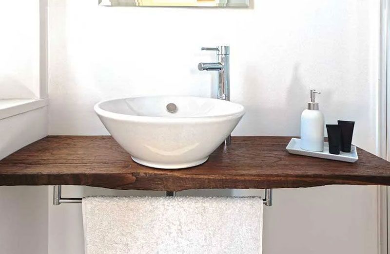 Ein weißes Waschbecken in einem Badezimmer auf einem Holzbrett