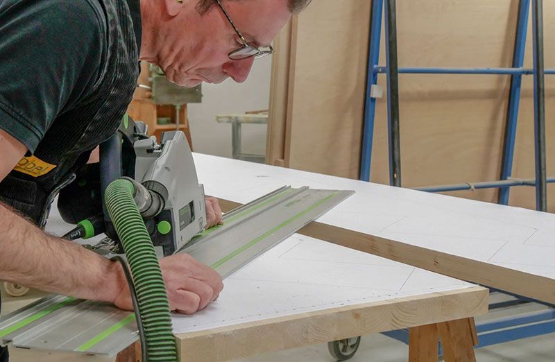 Ein Grübbel-Arbeiter beim Säge mit einer elektrischen Säge