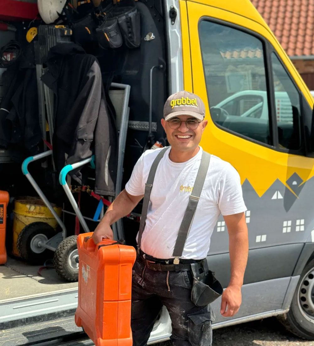 Ein Arbeiter von Grübbel vor einem Firmenwagen