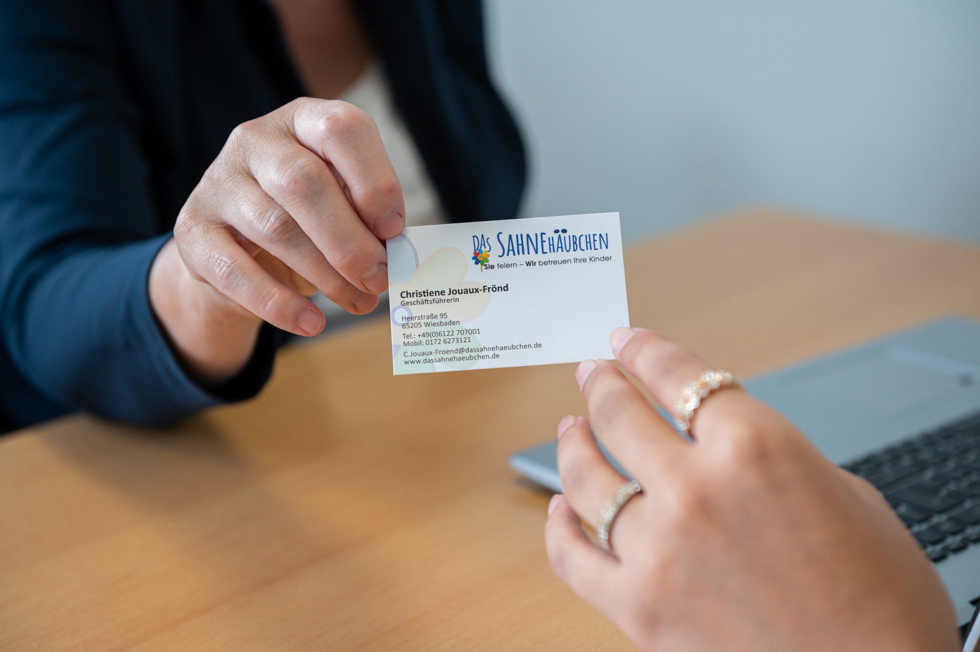 Christiene Jouaux-Frönd ist eine kompetente Ansprechpartnerin für alle Fragen der Franchisenehmerinnen. Überreichen einer Visitenkarte.