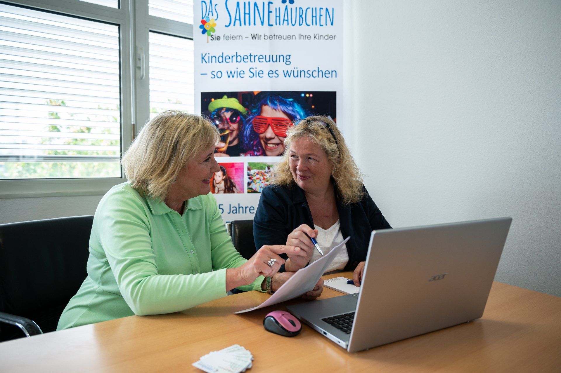 Das Sahnehäubchen Franchisekonzept - ein niedrigschwelliges Gründerinnenangebot für Frauen jeden Alters. Zwei Frauen am Schreibtisch vor einem Laptop im Business-Gespräch.