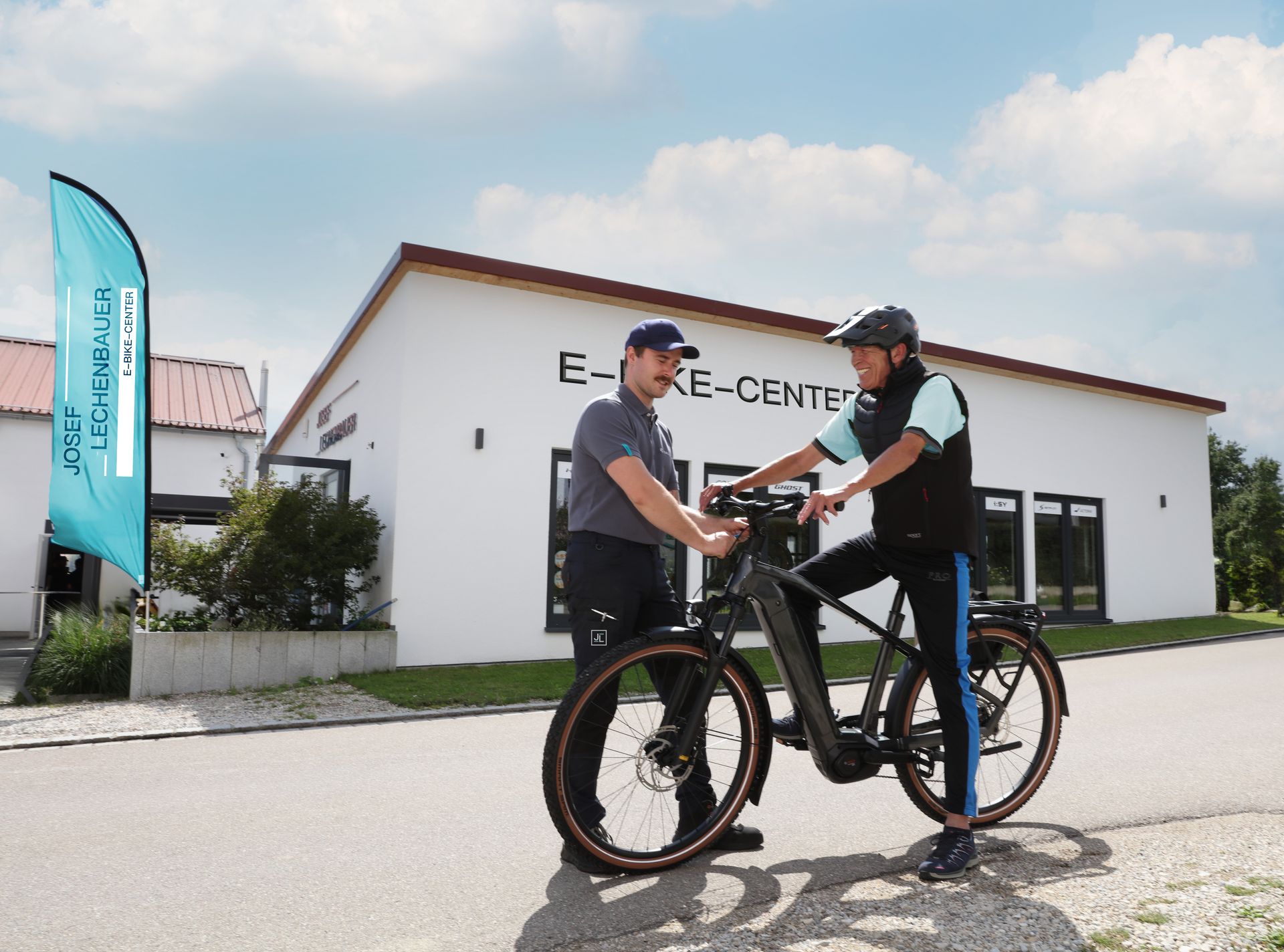 Dorian Stürz Berät einen Kunden vor dem Fahrradgeschäft E-Bike-Center Lechenbauer