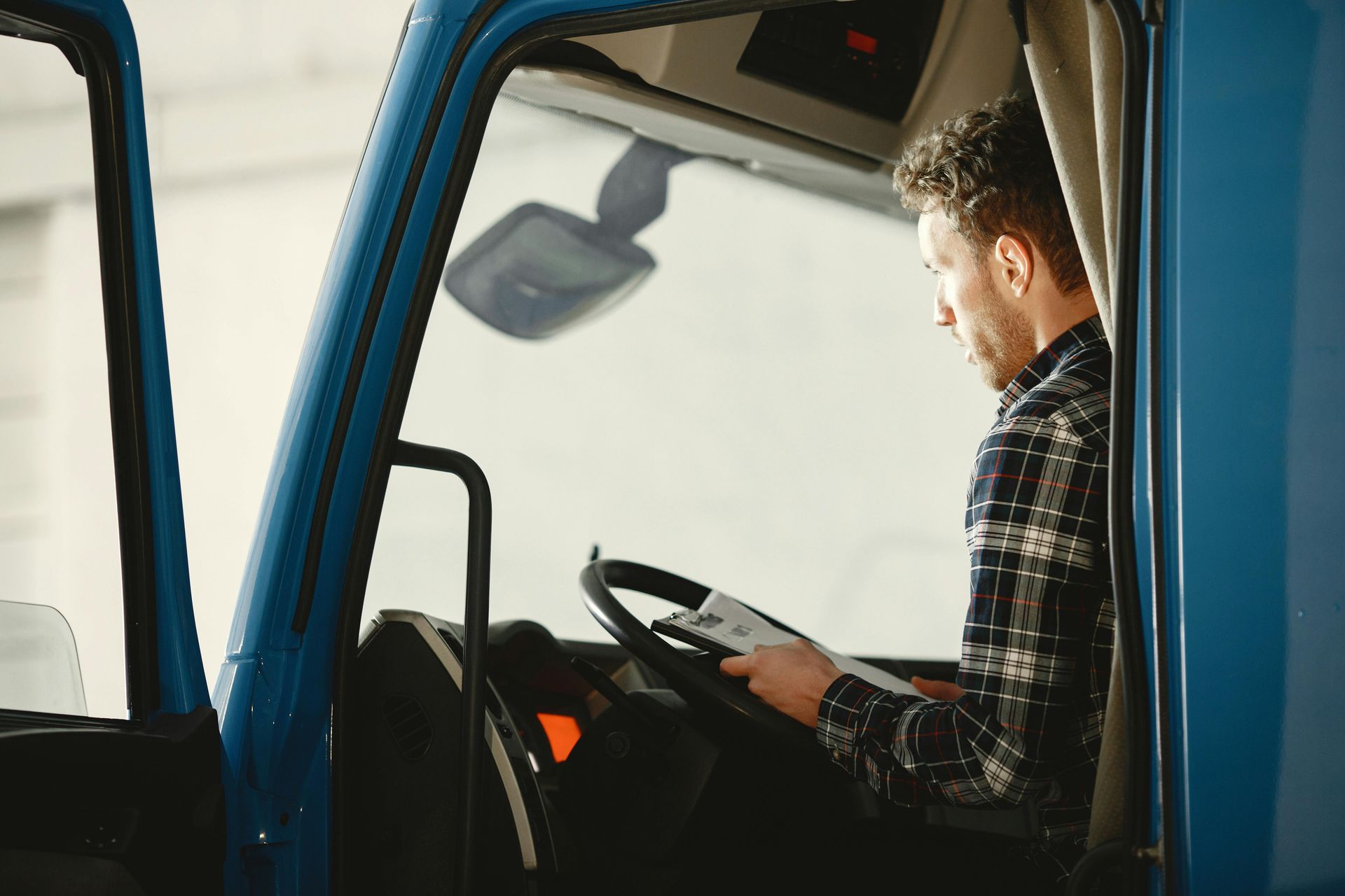 Hombre sentado en cabina de camion con libreta en mano.