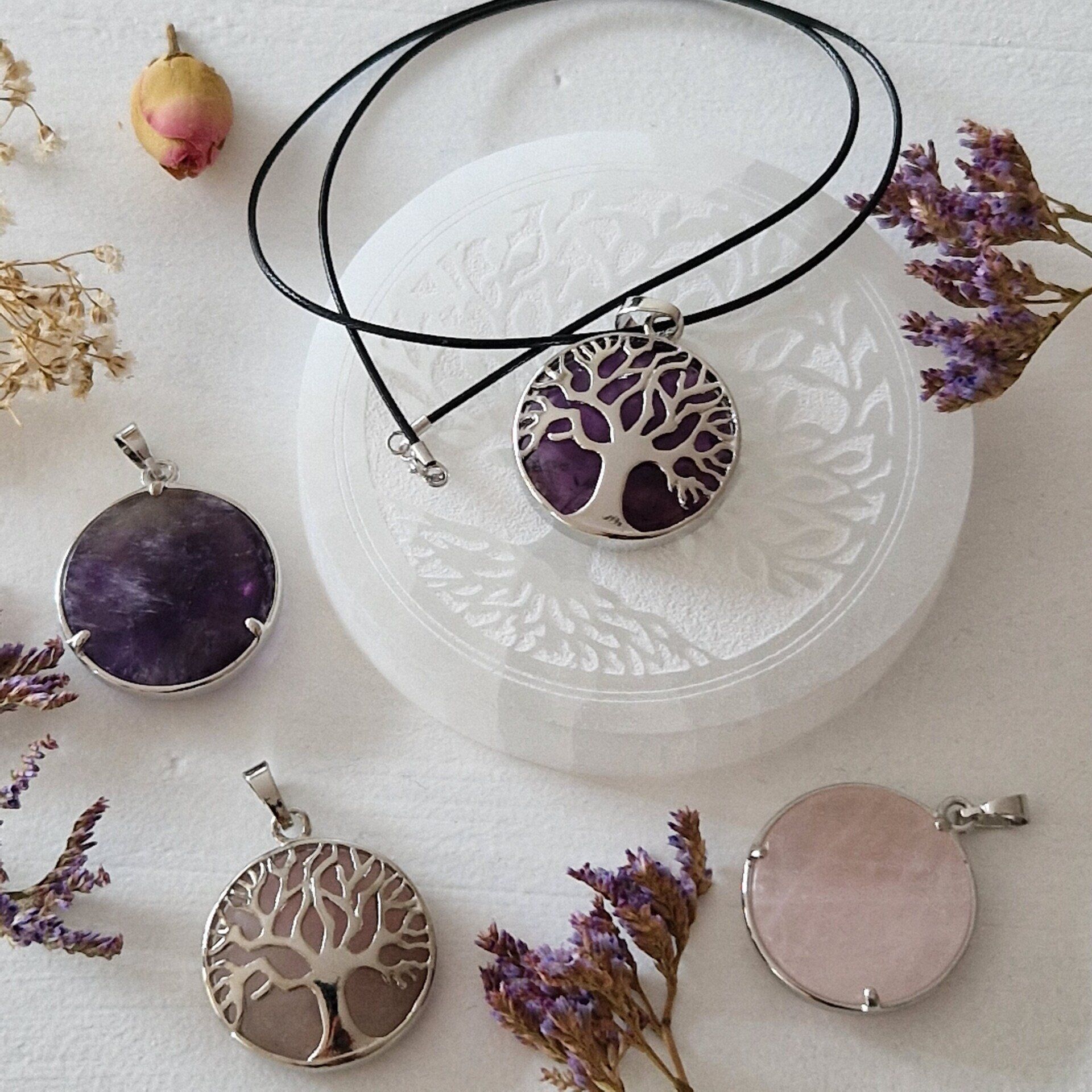 Des colliers élégants ornés d'arbres de vie, délicatement posés sur des disques de sélénite.