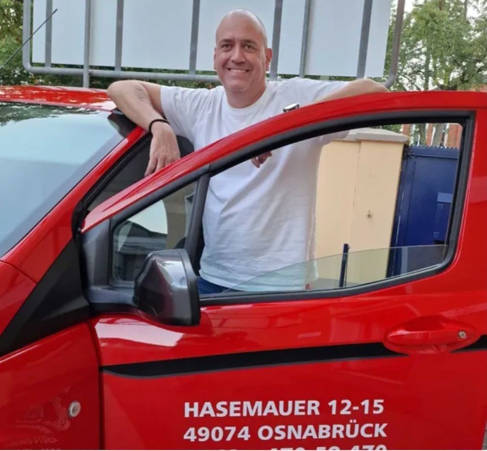 Ihr Monteur steht an seinem Fahrzeug und lächelt in die Kamera