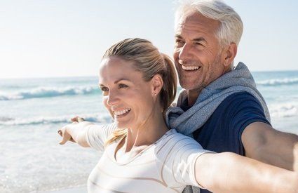 Partnerschaft leben und erleben Lifecoaching mit Hypnocentro - Beziehungscoaching - Senioren paar lächelt glücklich am Strand und zeigt sich als harmonische Einheit